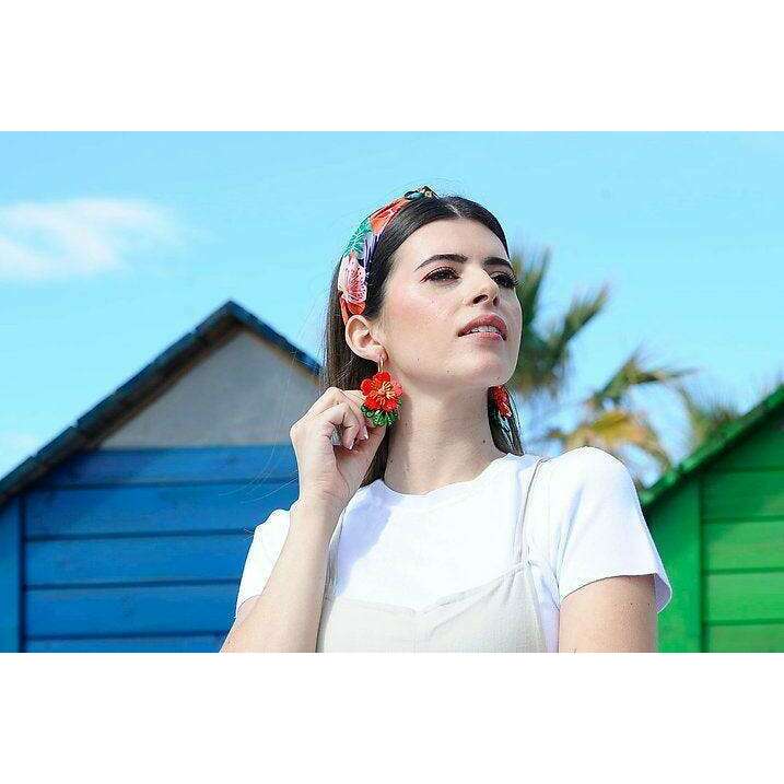 Red tropical flower earrings on ear: red flowers, green leaves, light green cone drops