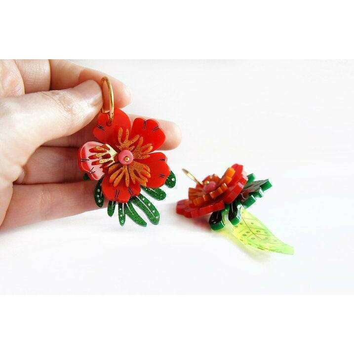 Red tropical flower earrings close-up: gold hooks, red blossoms, green leaves, light green cone drops