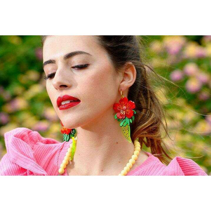 Red tropical flower earrings on ear: red blossoms, green leaves, light green patterned cone drops
