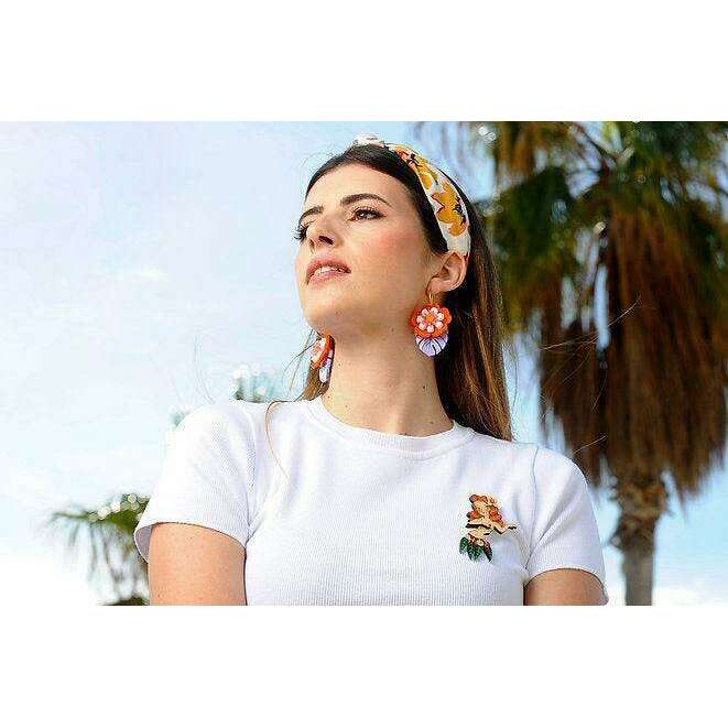 Redhead hula girl brooch on chest of white top, multicolor hula figure