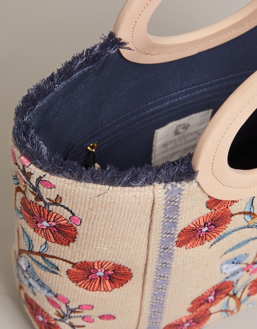 Close-up of floral tote interior with navy frayed trim, cream lining, and small label