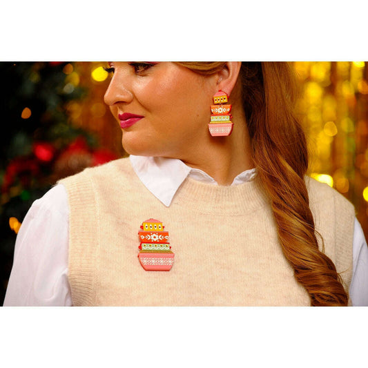 Retro container brooch worn on sweater vest, orange-and-white stack with gold details