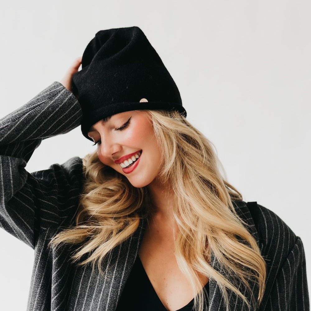 Black cashmere beanie with a rolled edge and small gold-tone logo
