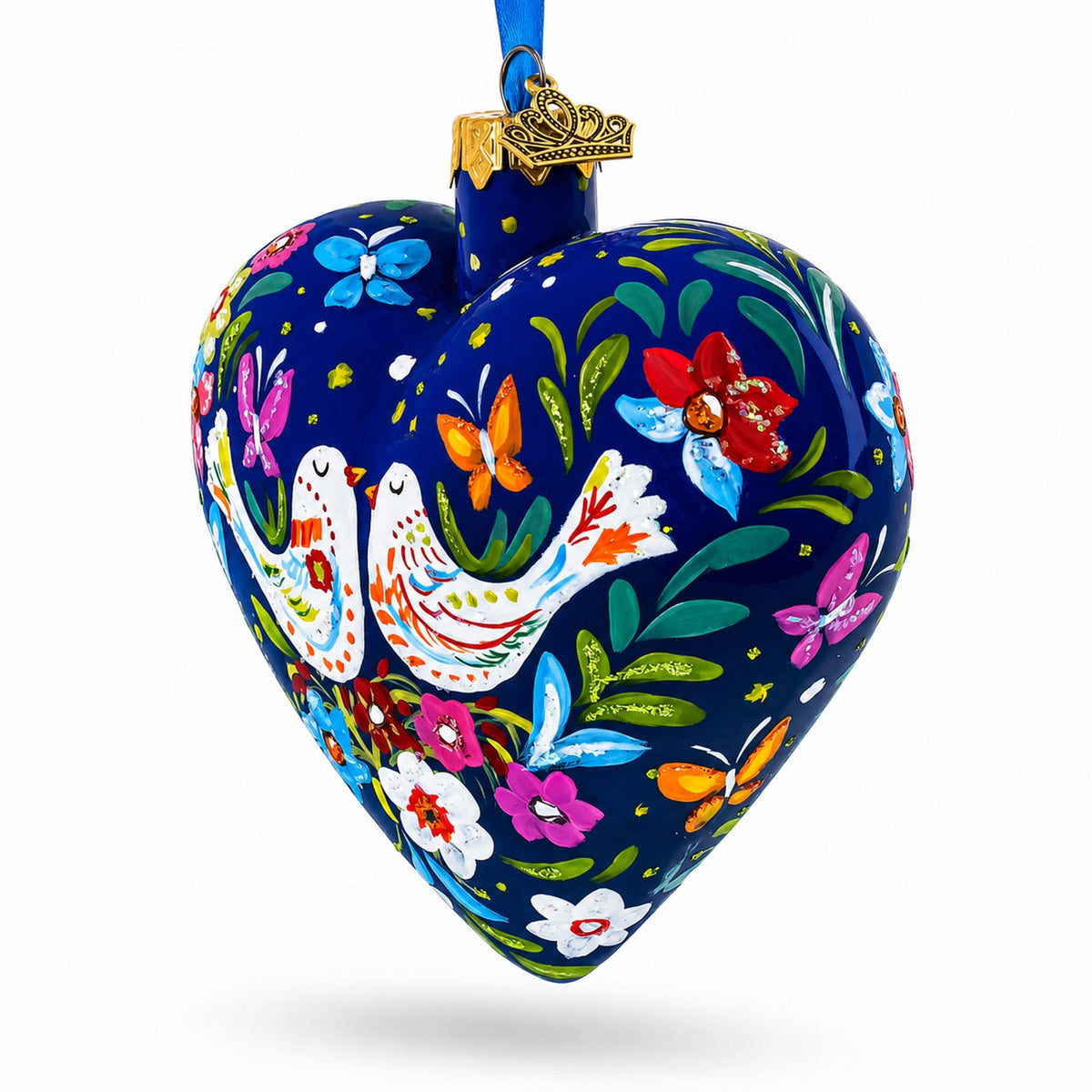 Heart-shaped blue glass ornament with folk bird and butterfly motifs, hanging from blue ribbon