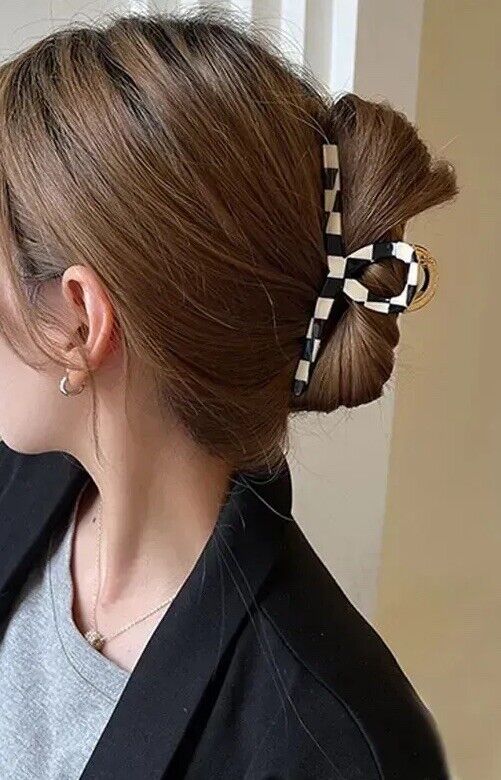 Black and white check hair claw with gold-tone detail clipped on a bun