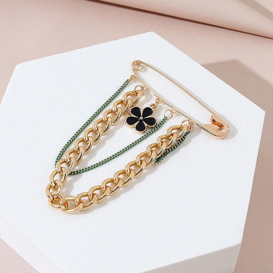 Gold-tone chain and black enamel flower brooch with pin clasp, green accents