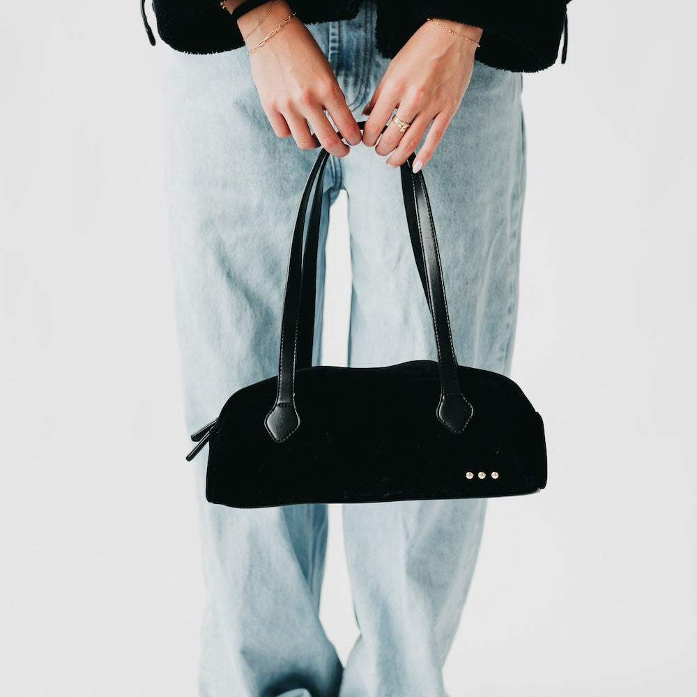 Black suede barrel shoulder bag with long handles and metal stud detail