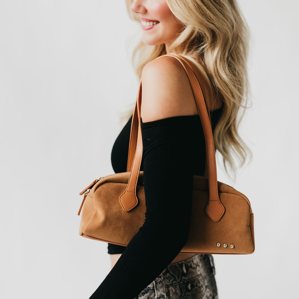 Camel suede barrel shoulder bag with long strap, zip top, and metal studs