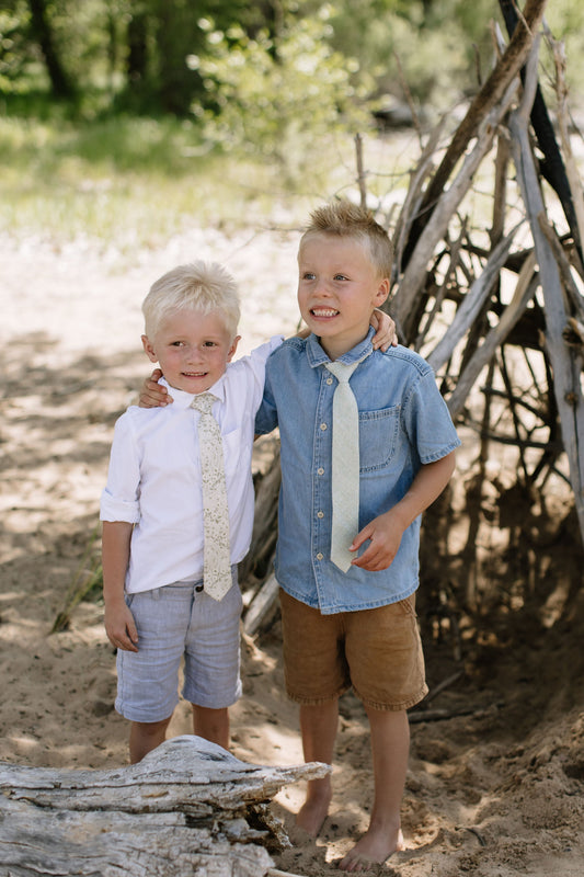 Boys slim necktie with light floral pattern, worn under a button-up shirt.