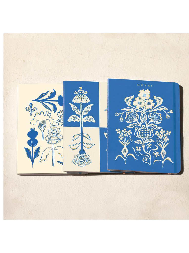 Three floral notebooks laid flat together, blue and cream printed covers