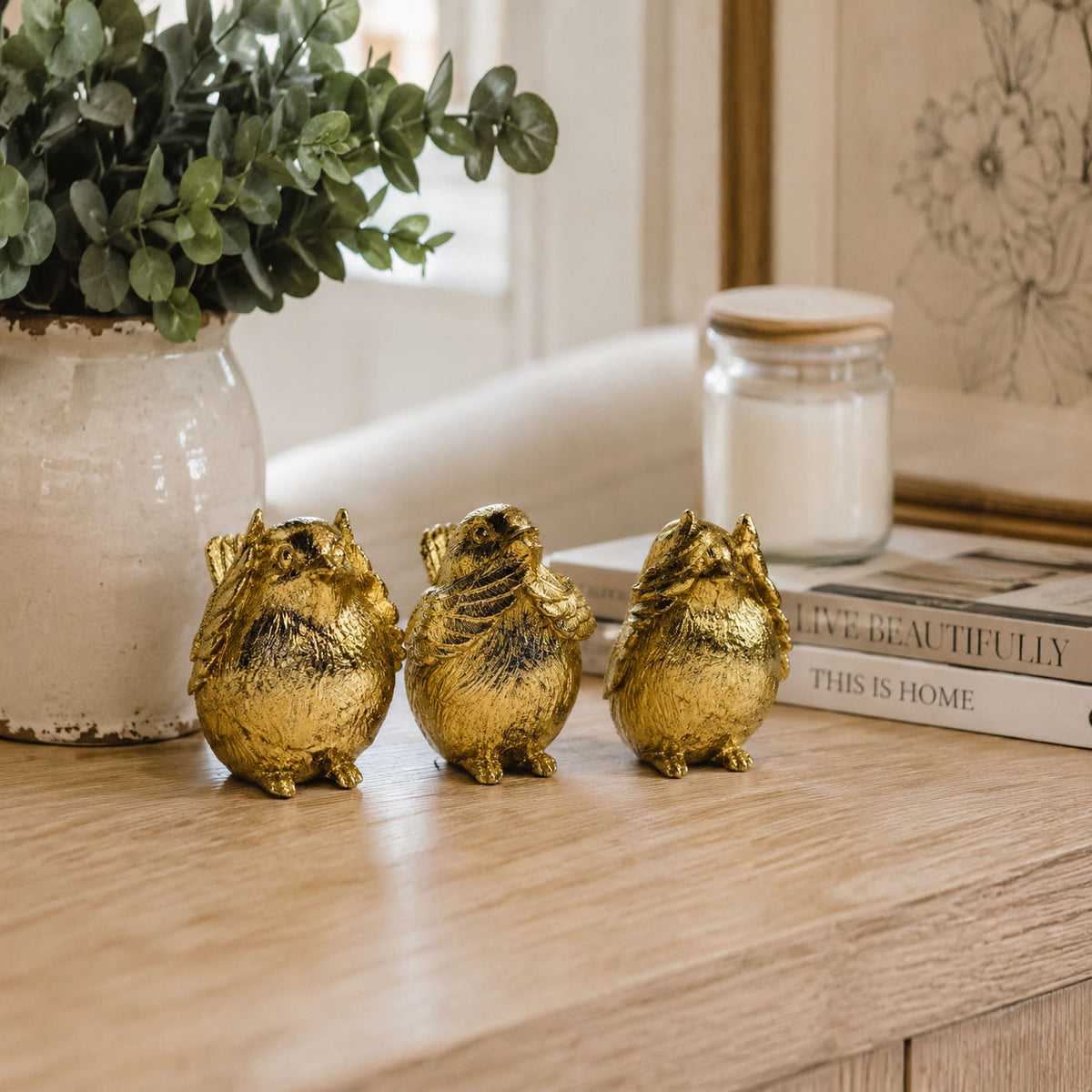 Set of three gold-tone bird figurines with textured feather detail on a tabletop