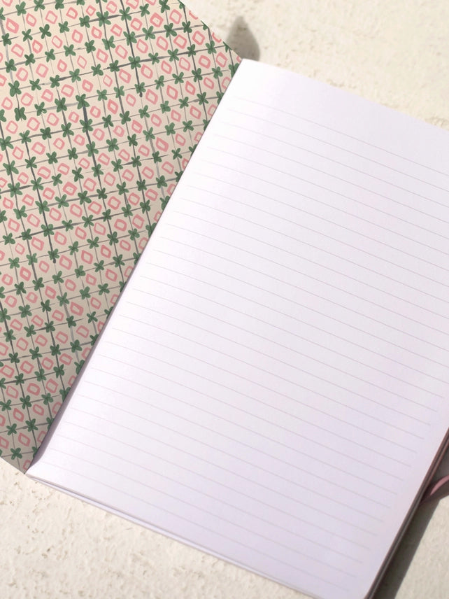Open notebook with lined pages and patterned cover featuring small red flower icons