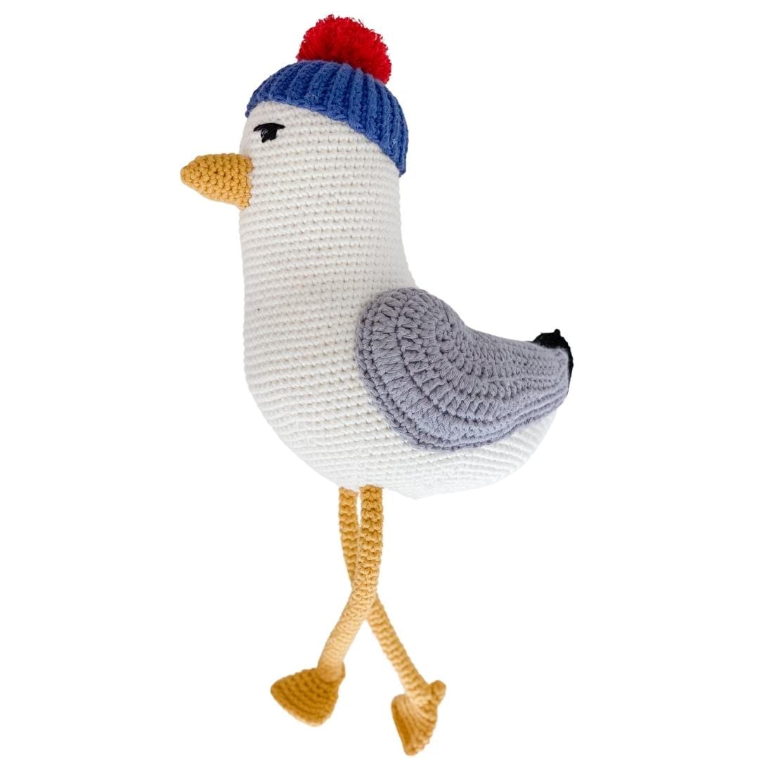 Side view of a crocheted seagull plush with crossed yellow legs and gray wings