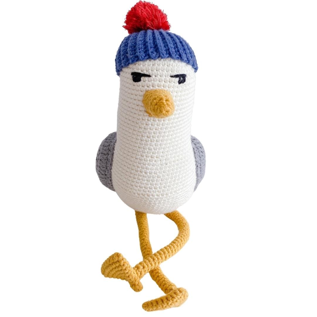 Front view of a crocheted seagull plush with a blue cap and red pom-pom