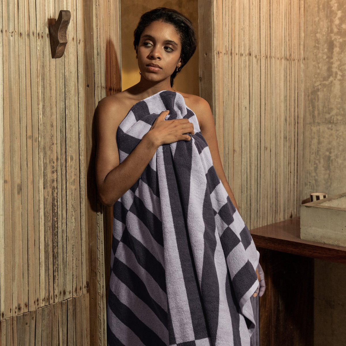 Checkered cotton towel in lilac and charcoal stripes, wrapped around a person