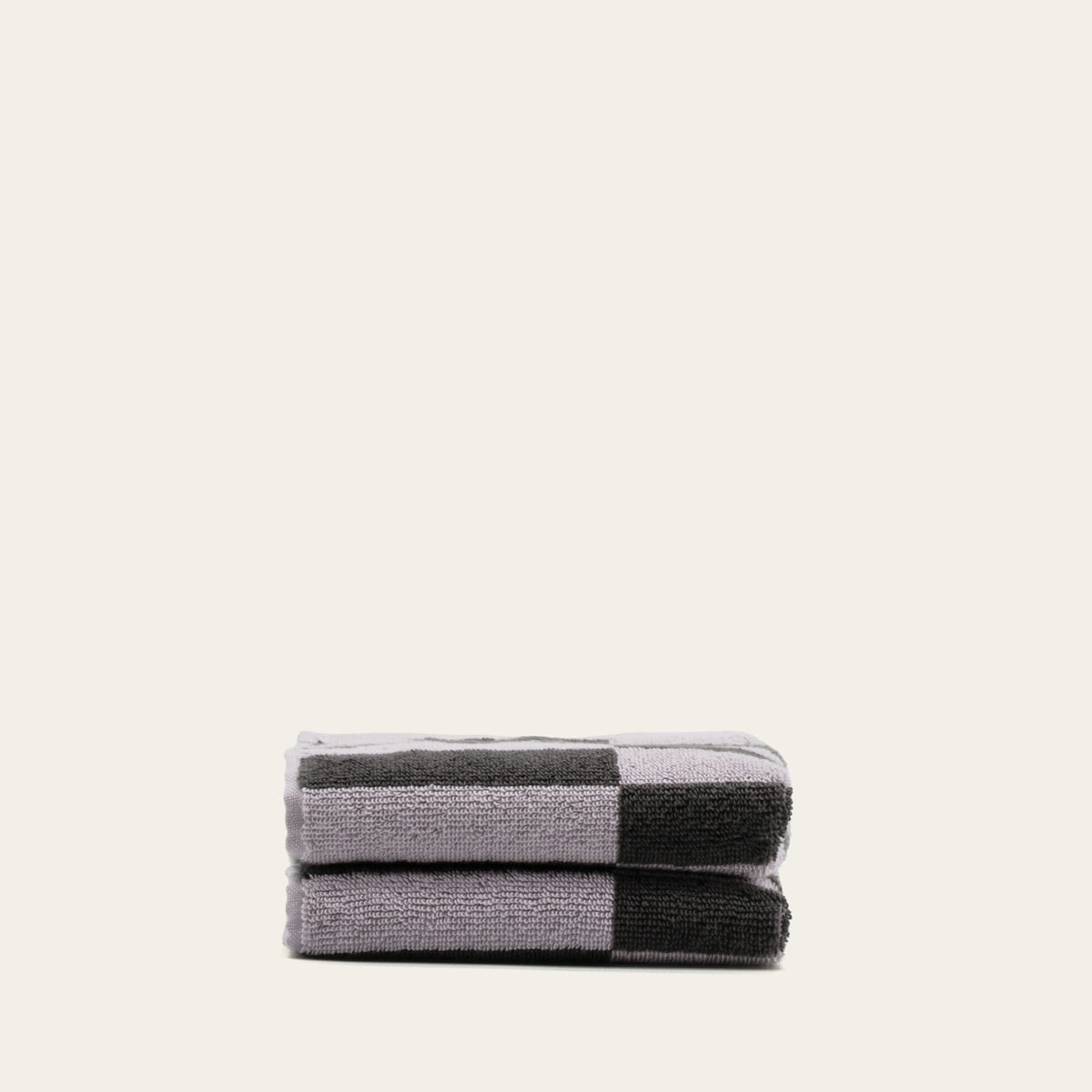 Stack of folded checkered cotton towels in lilac and charcoal stripes