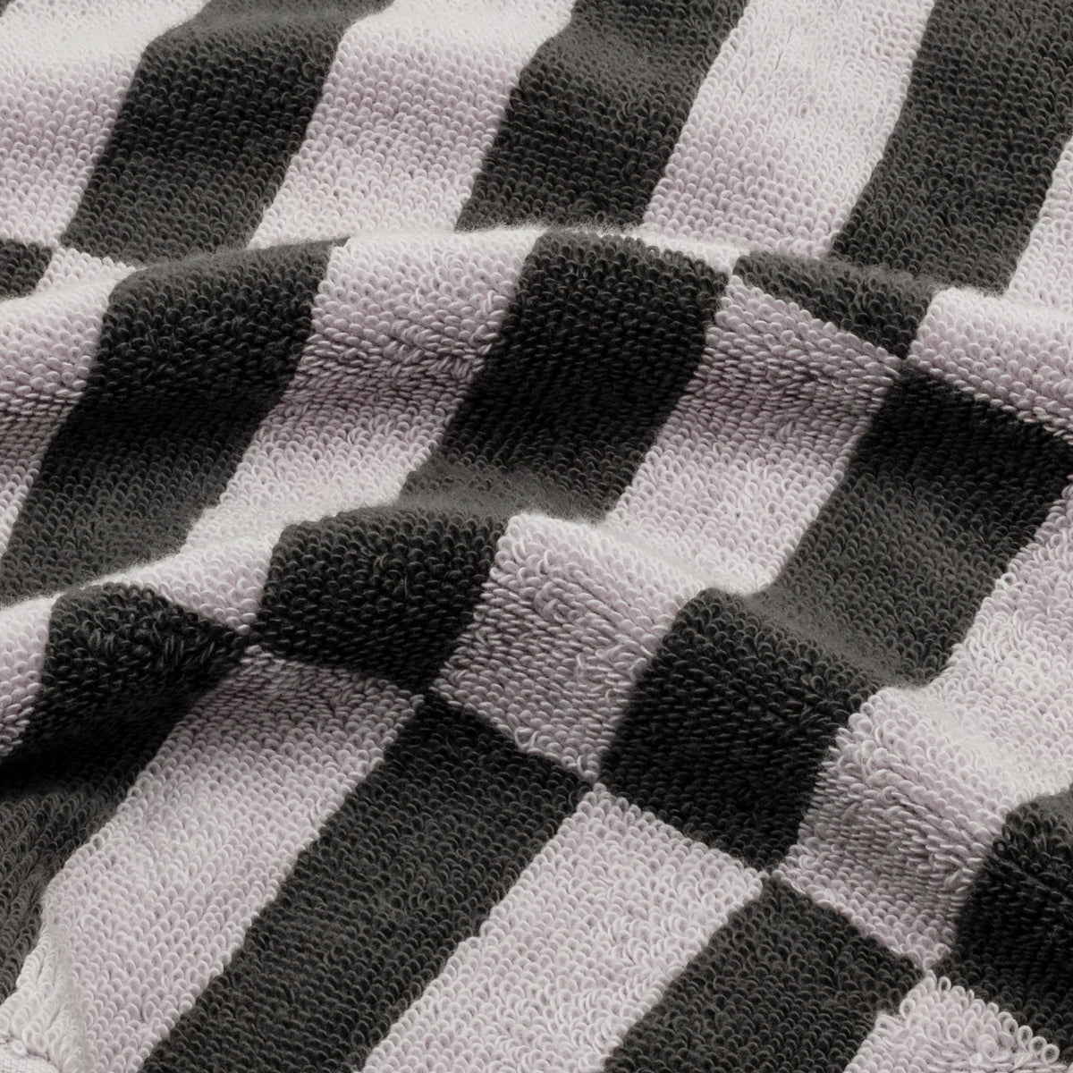 Close-up of checkered cotton towel fabric in lilac, black, and charcoal stripes