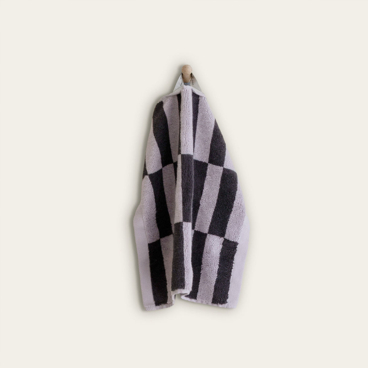 Folded checkered cotton towel in lilac and charcoal stripes on a light background