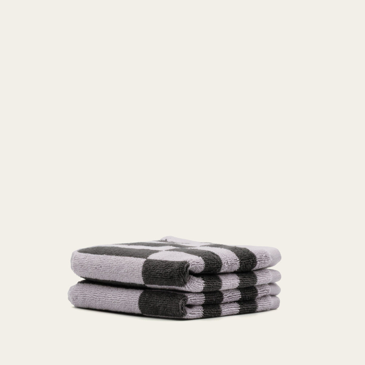 Stacked rolled checkered cotton towels in lilac and charcoal stripes