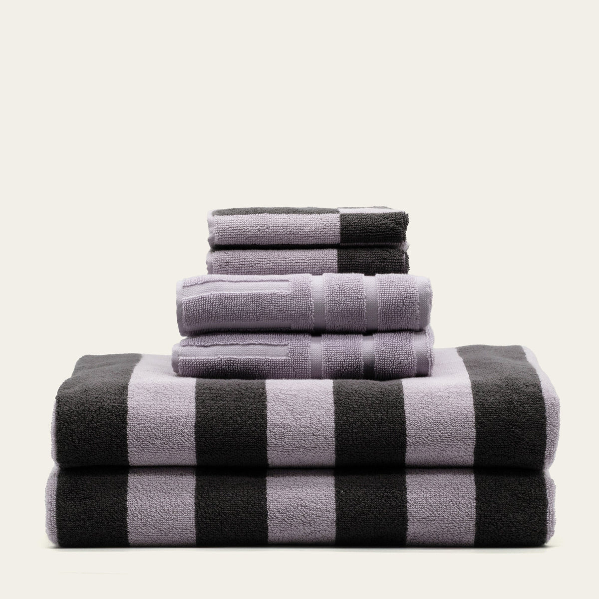 Folded cotton towels in lilac and charcoal with bold checkered stripe pattern