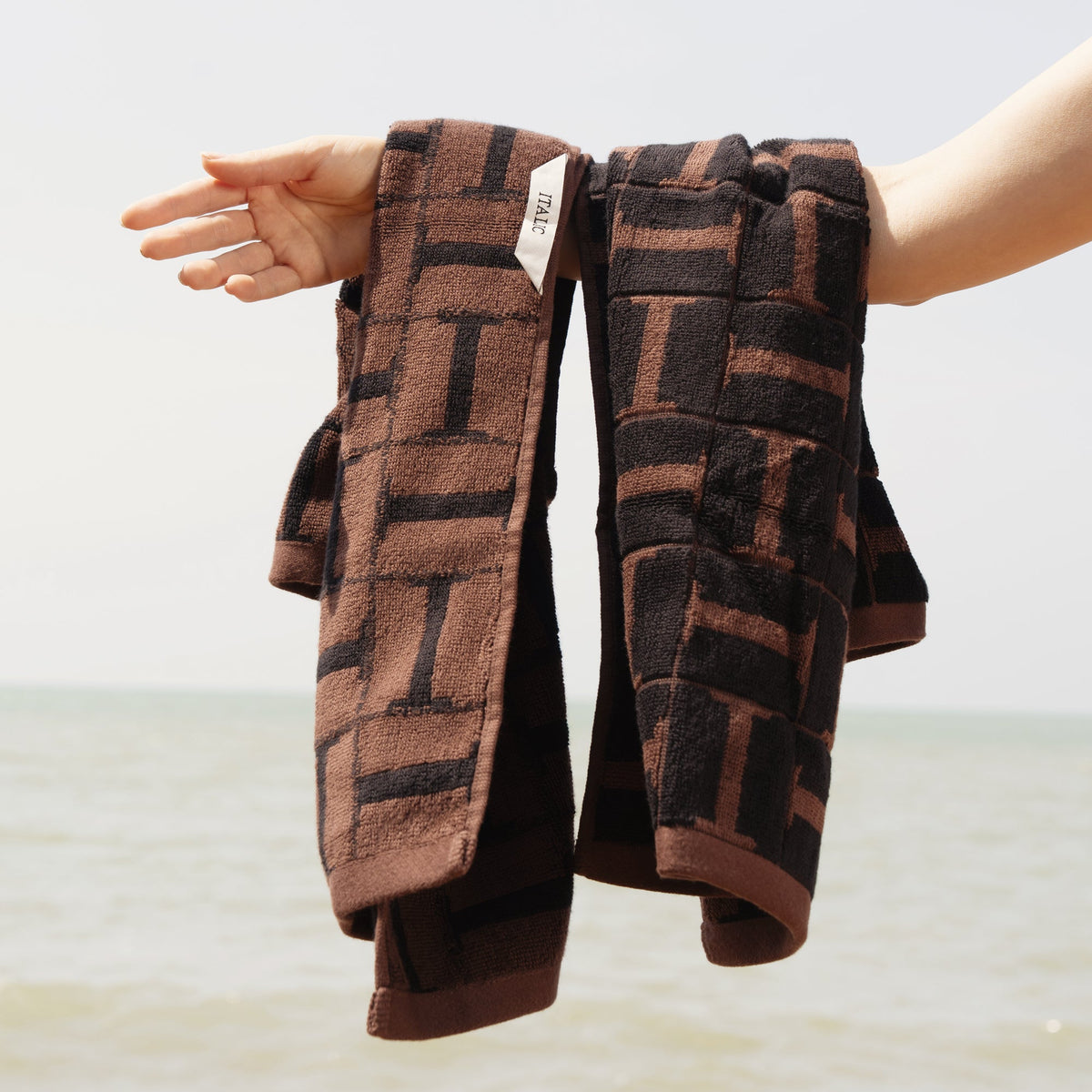 Brown and black plaid cotton towels, folded, with label visible on edge