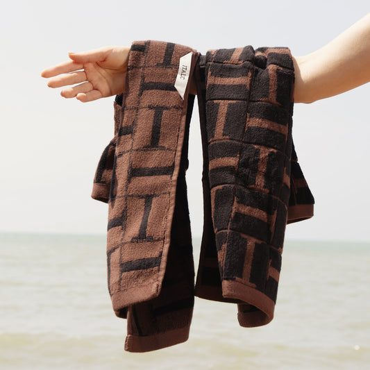 Brown and black plaid cotton towels, folded, with label visible on edge