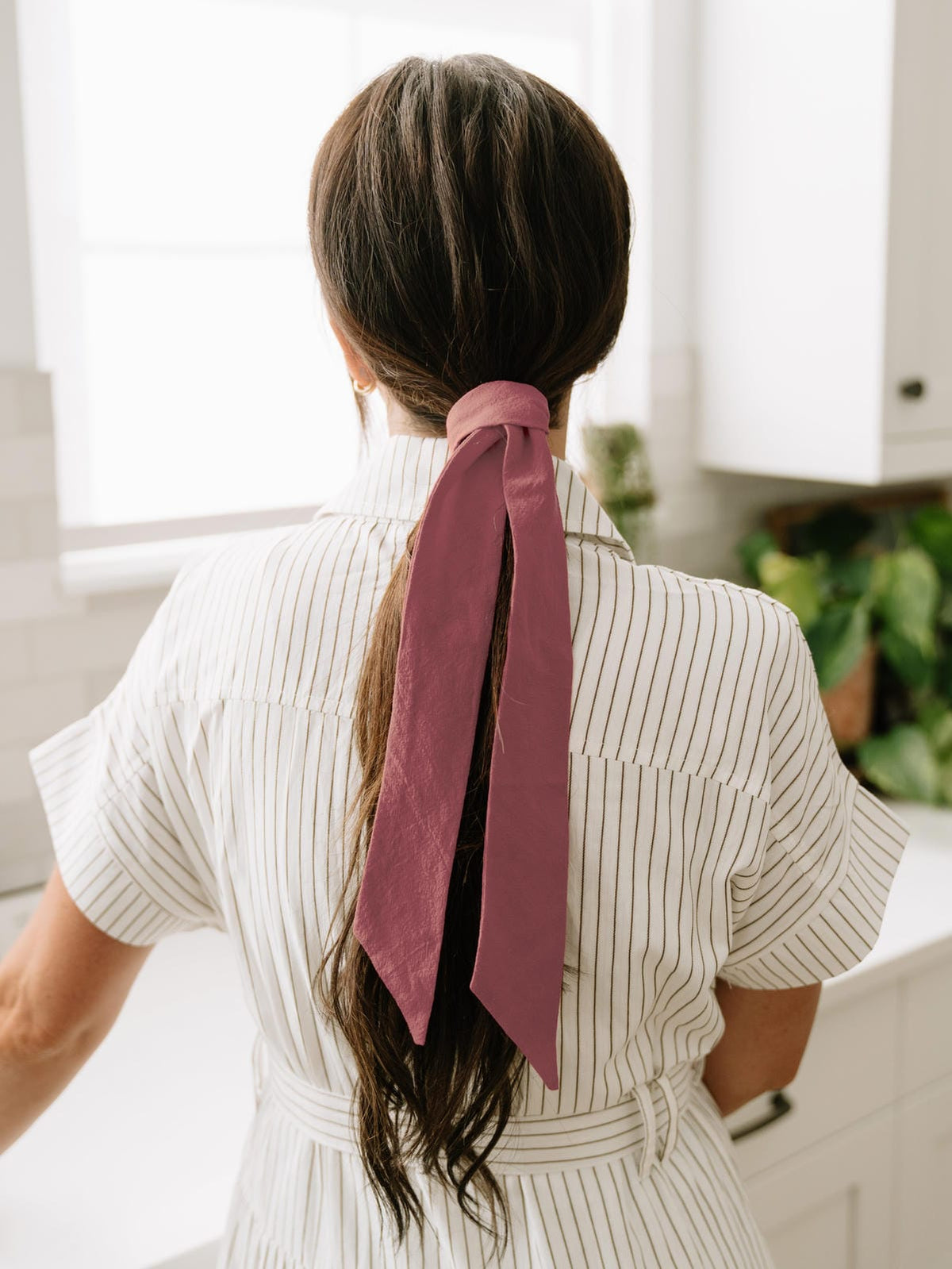 Burgundy floral hair sash tied in ponytail, long trailing ribbon ends