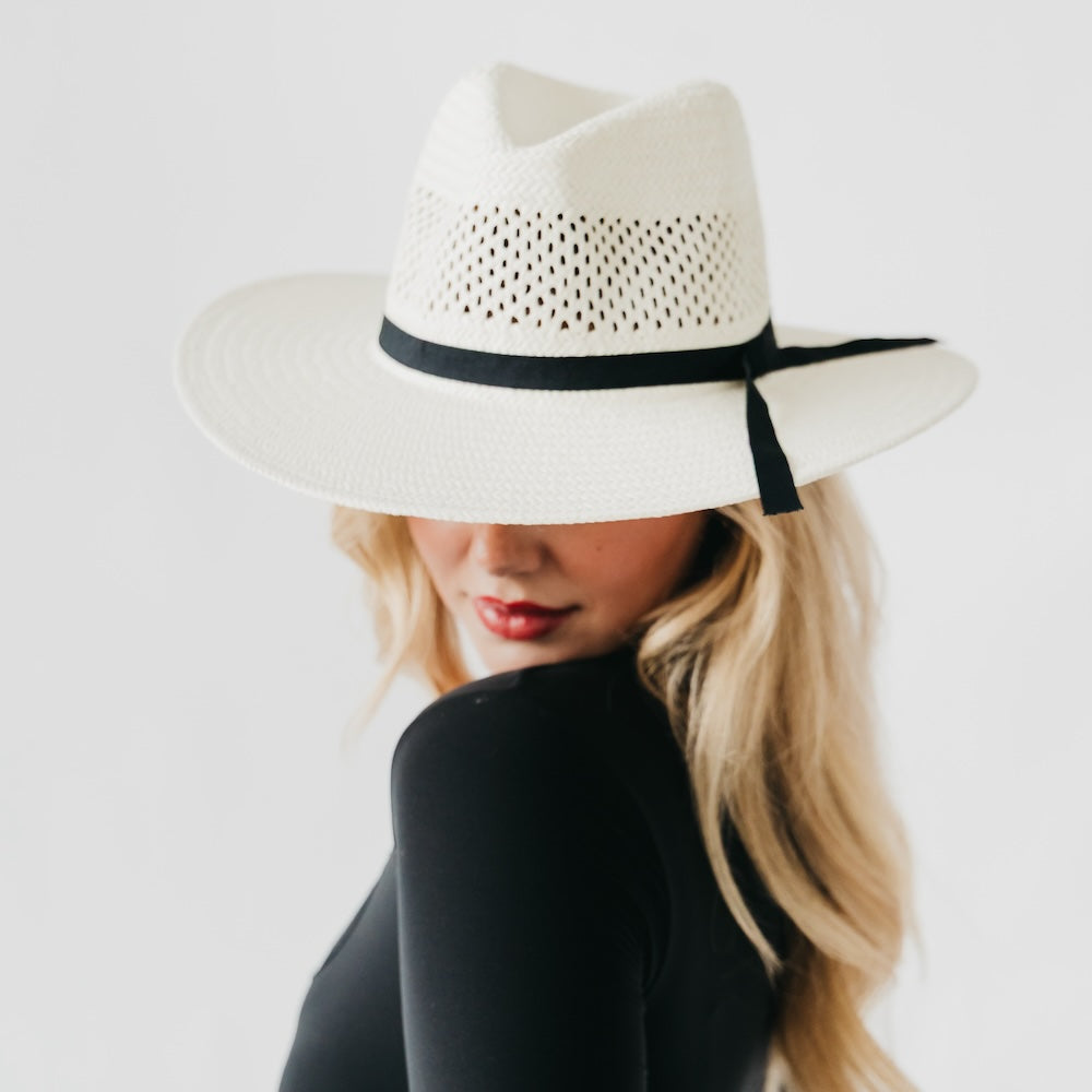 White perforated western sun hat with black band and ribbon bow, wide brim.