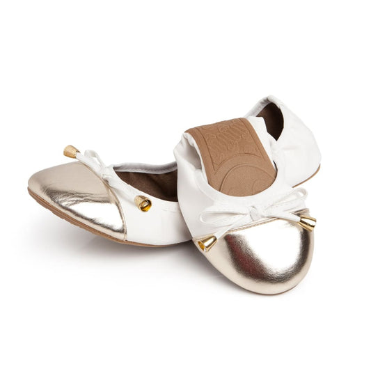 White flats with metallic gold toe and white bow laces, low flat sole