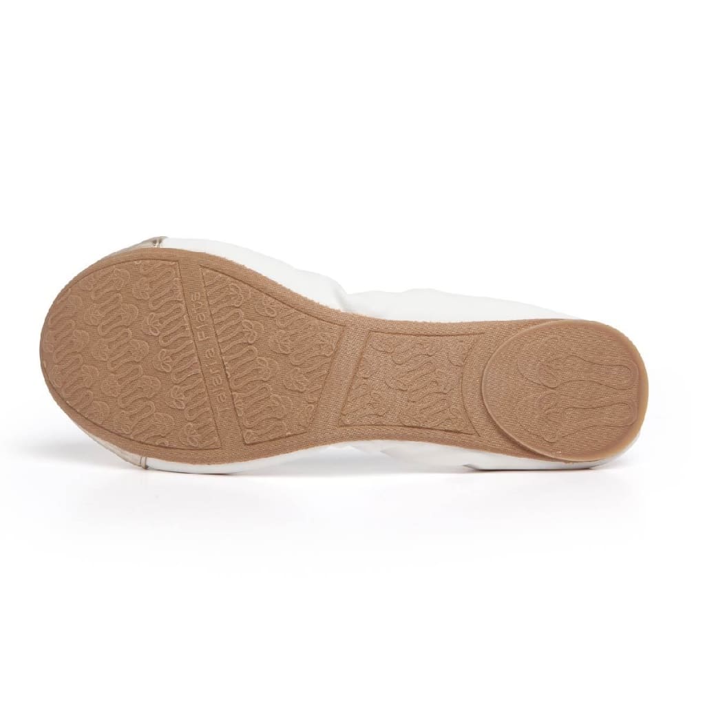 White flats with metallic toe, textured tan rubber sole view