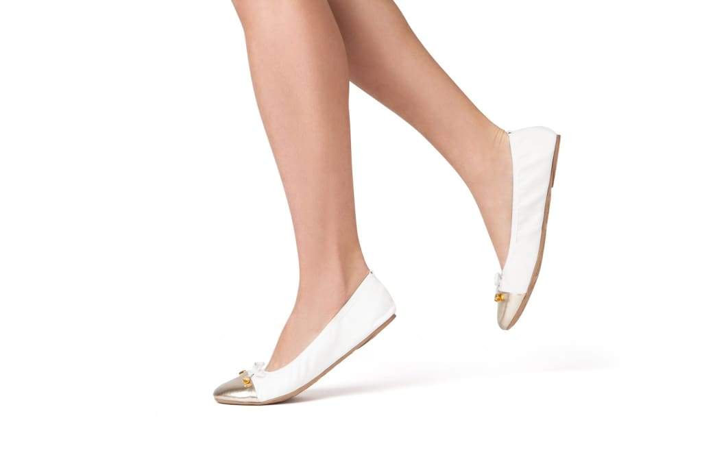 White flats with metallic toe, worn with bare feet and low flat heel