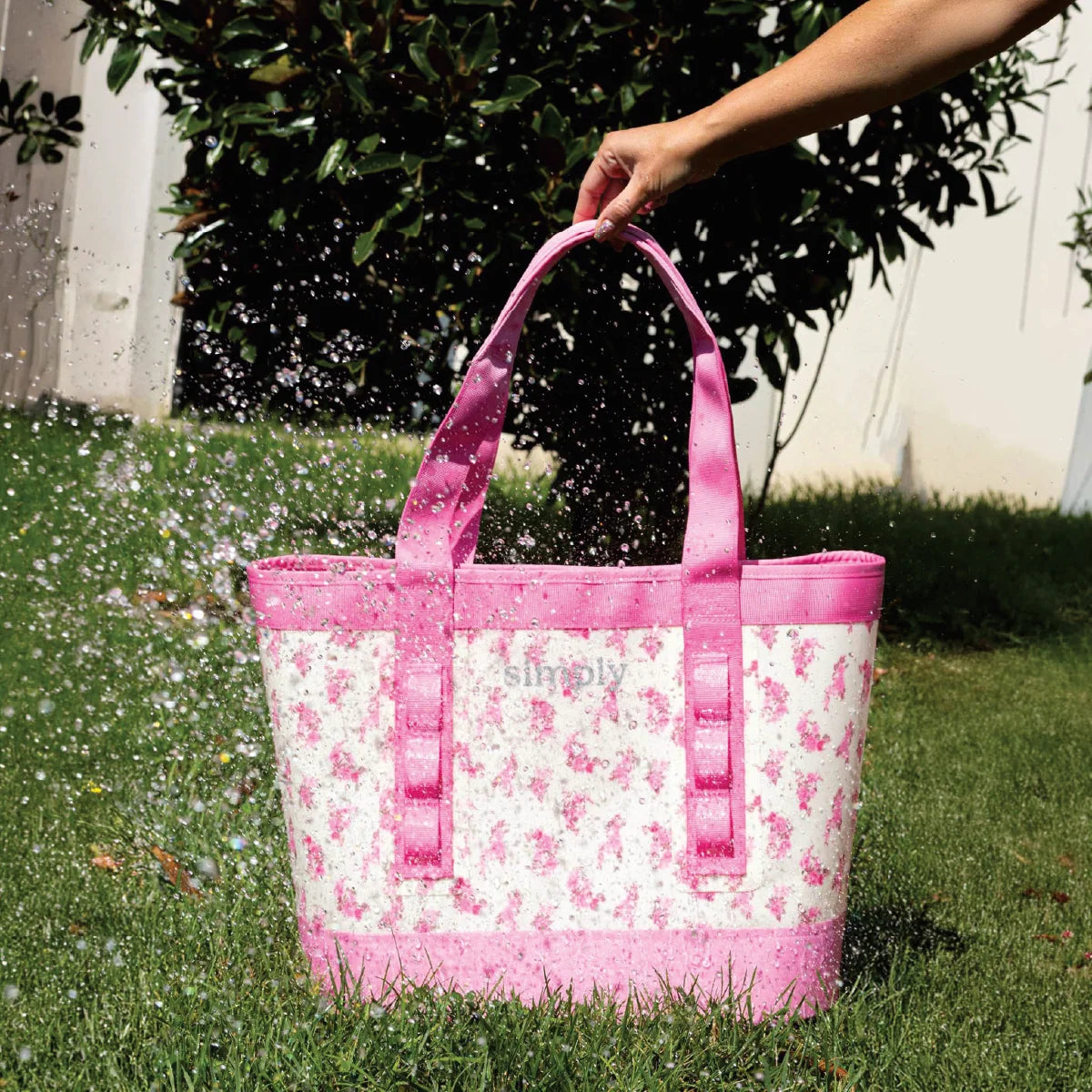 Pink floral tote bag with sturdy straps, held open with front pocket and 'Simply' logo