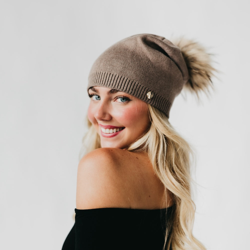 Mocha knit slouchy beanie with ribbed cuff, gold-tone button, and fur pom