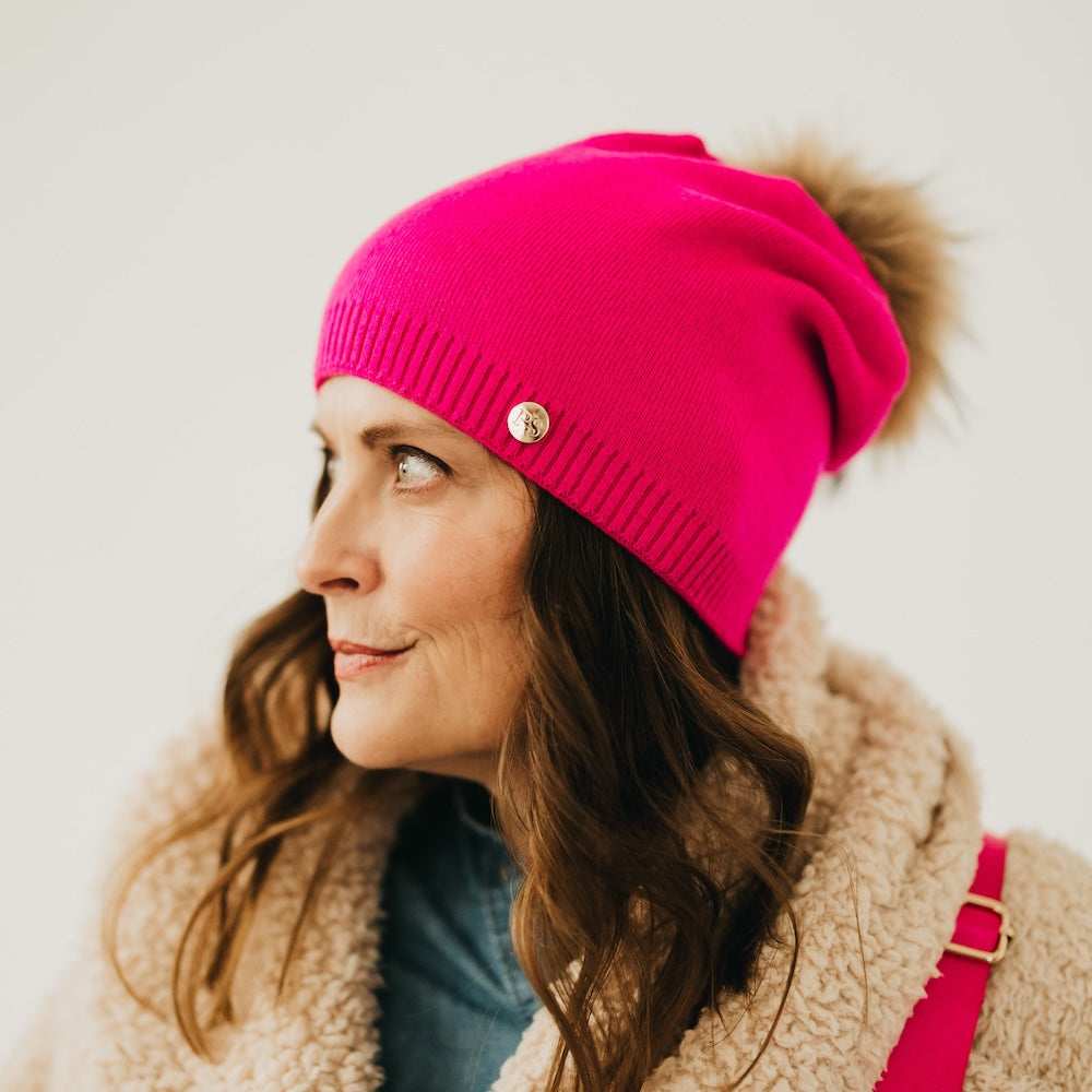 Fuchsia knit slouchy beanie with ribbed cuff, gold-tone button, and fur pom