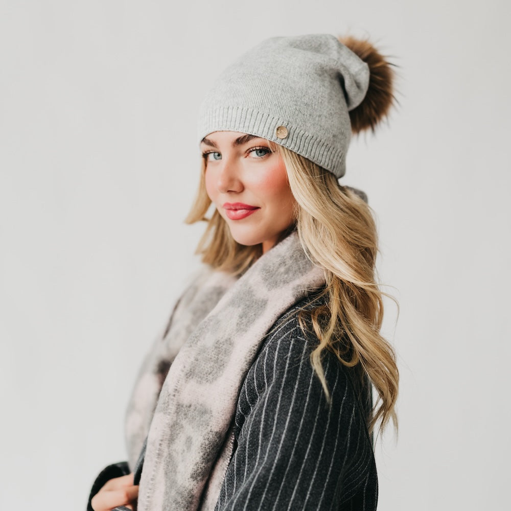 Light gray knit beanie with slouchy crown, ribbed cuff, and fur pom