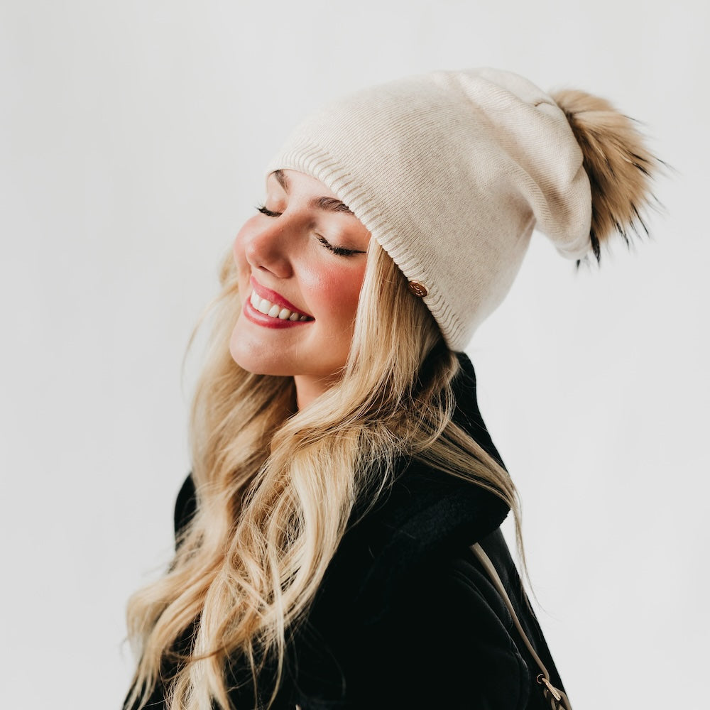Side view of cream slouchy beanie with fur pom