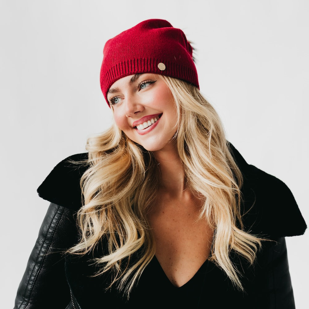 Red knit beanie with ribbed cuff and small metal emblem