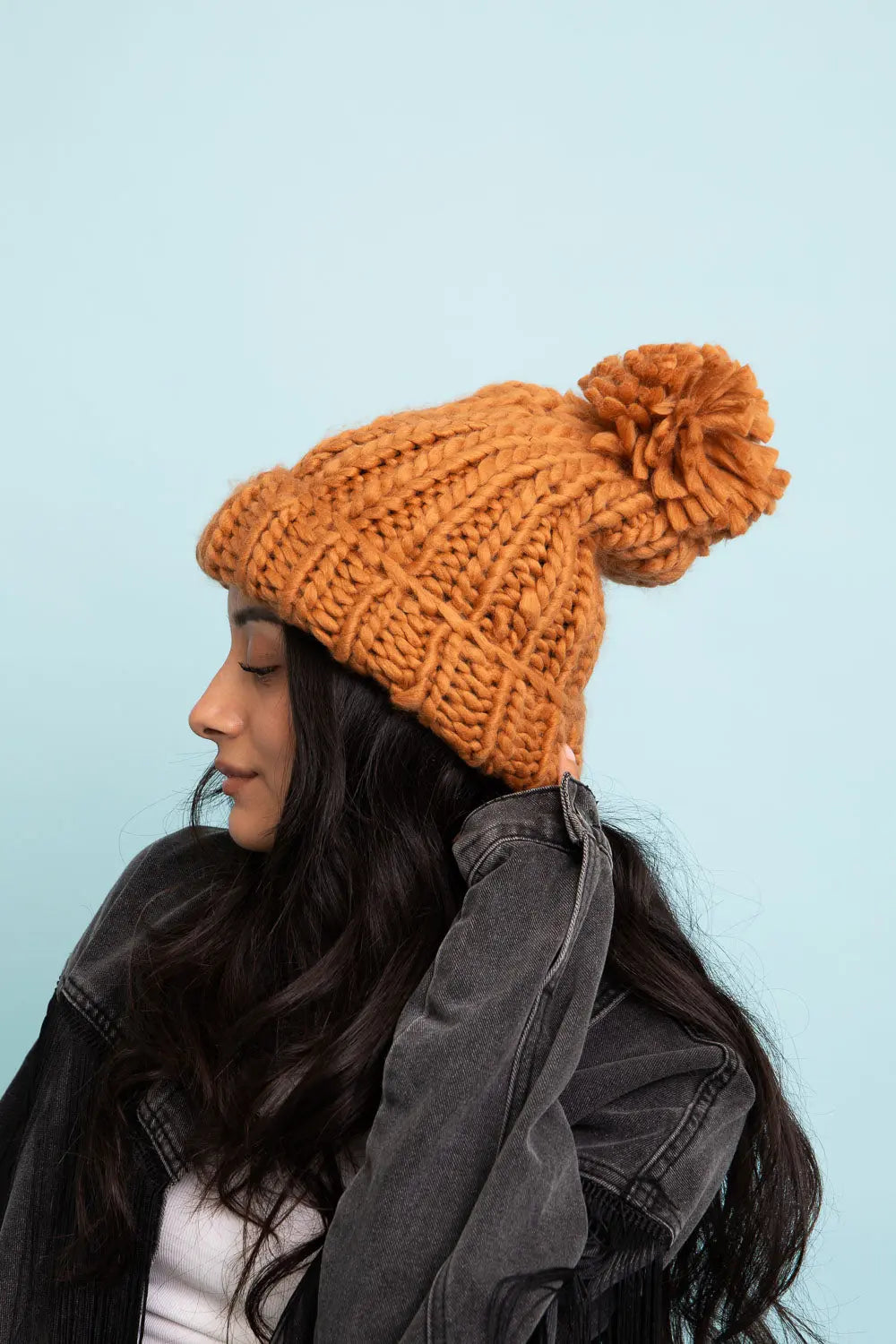 Camel cable-knit beanie with large pom-pom top and ribbed cuff, side view