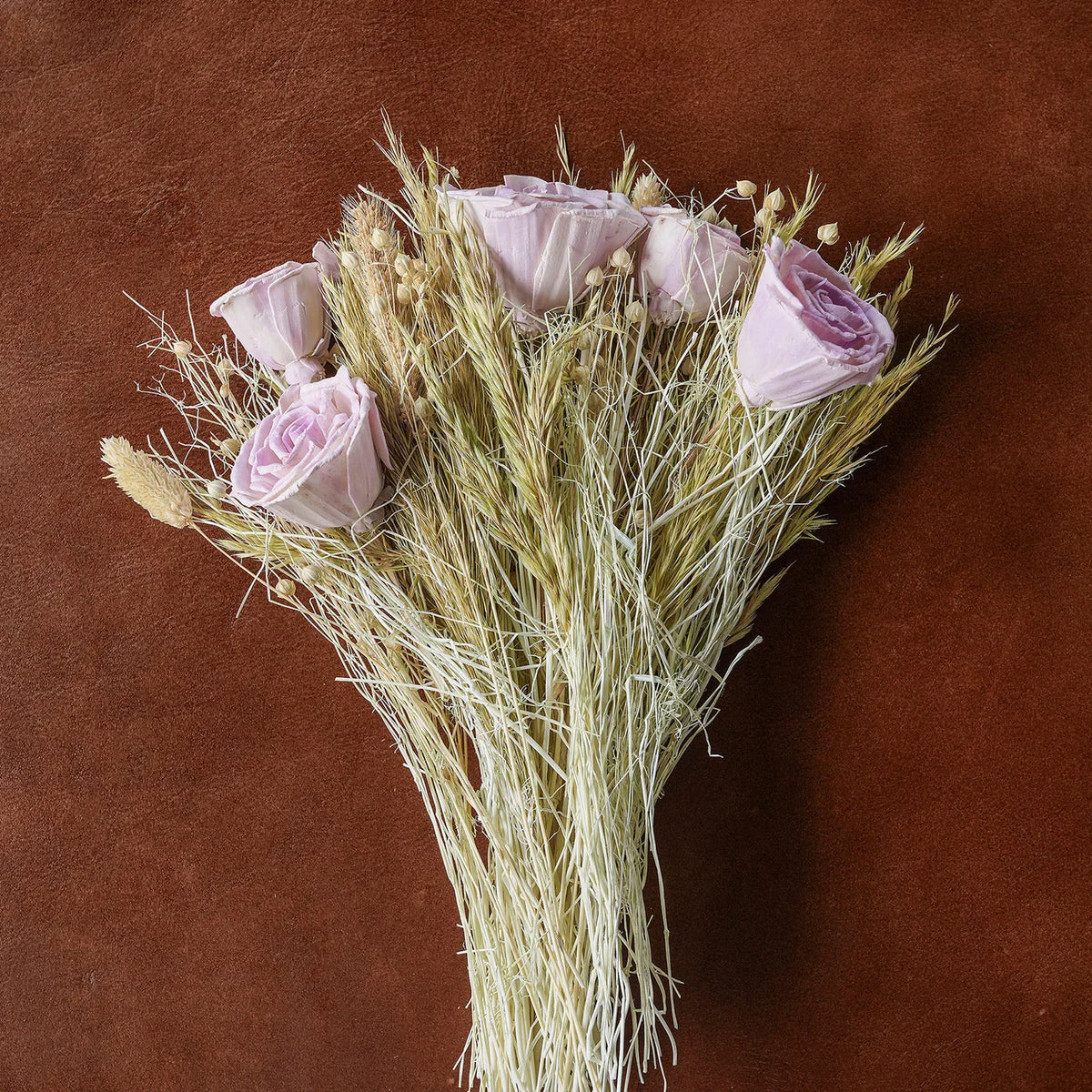 Dried floral bouquet with pale pink flower buds and straw-colored grasses