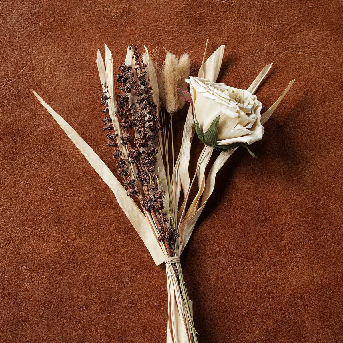 Dried floral bouquet with white and dark brown grasses and cream rose-like blooms