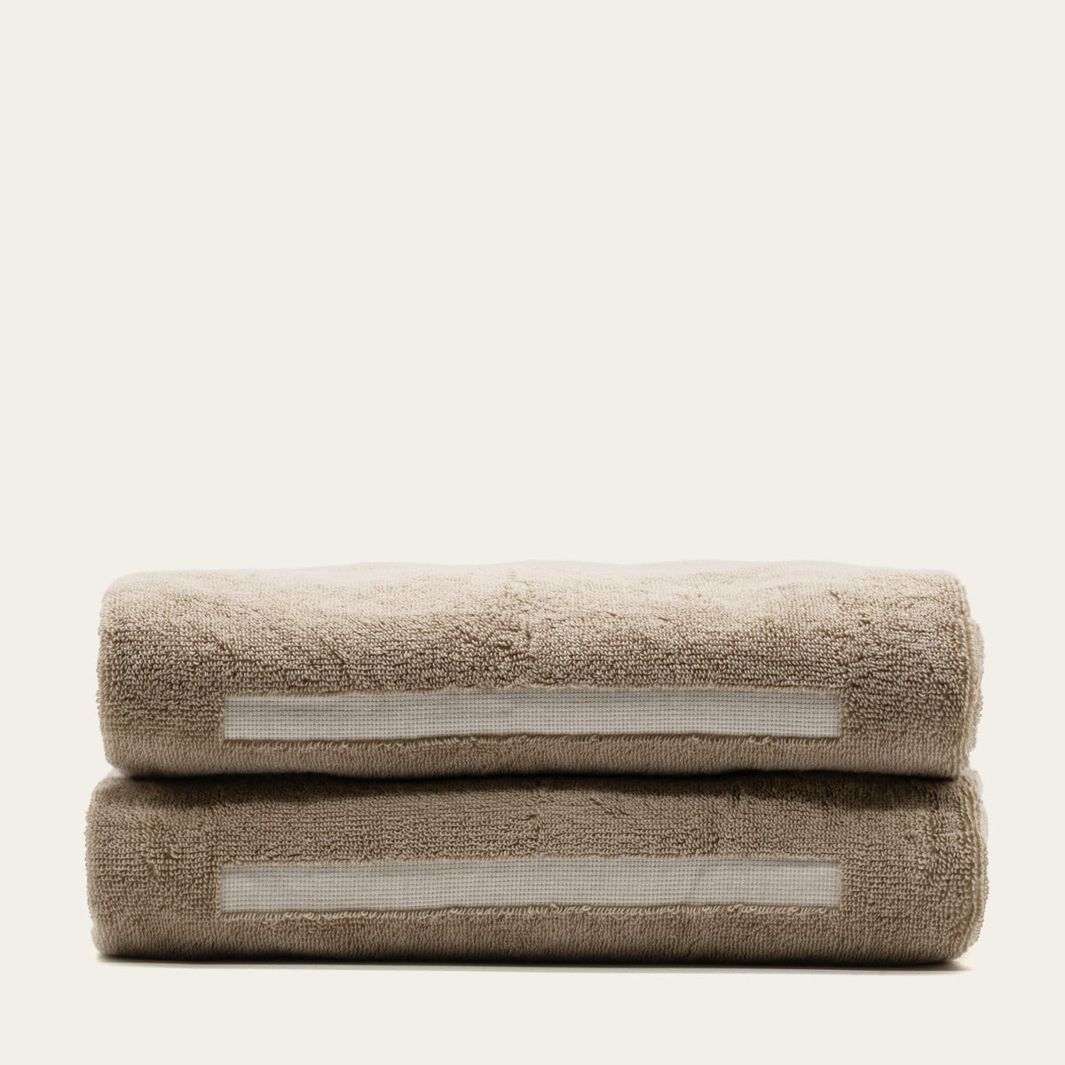 Tan and ecru cotton washcloths stacked, each with white stripe detail