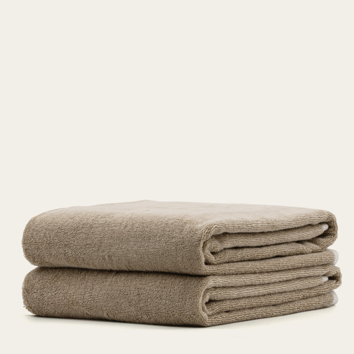 Stack of tan and ecru cotton towels with white stripe accents