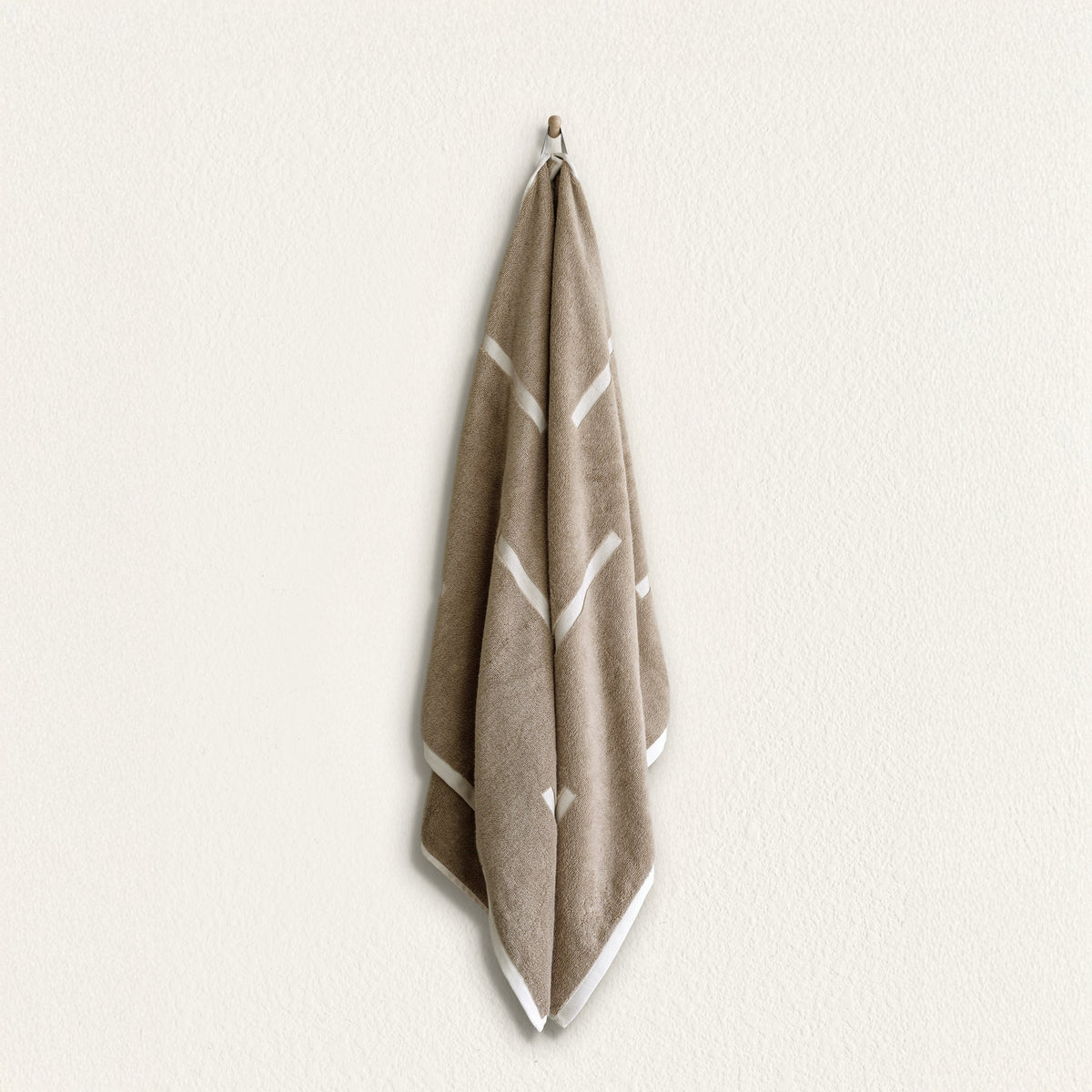 Tan and ecru cotton towel with white geometric stripe pattern and hanging loop