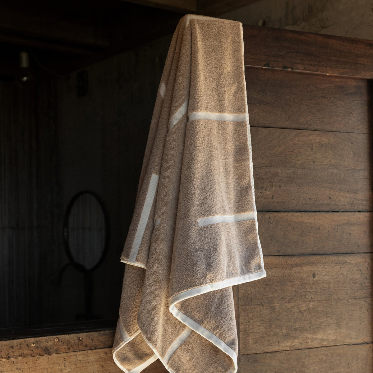 Sorrel Australian cotton bath towel in tan with ecru stripe border, hanging