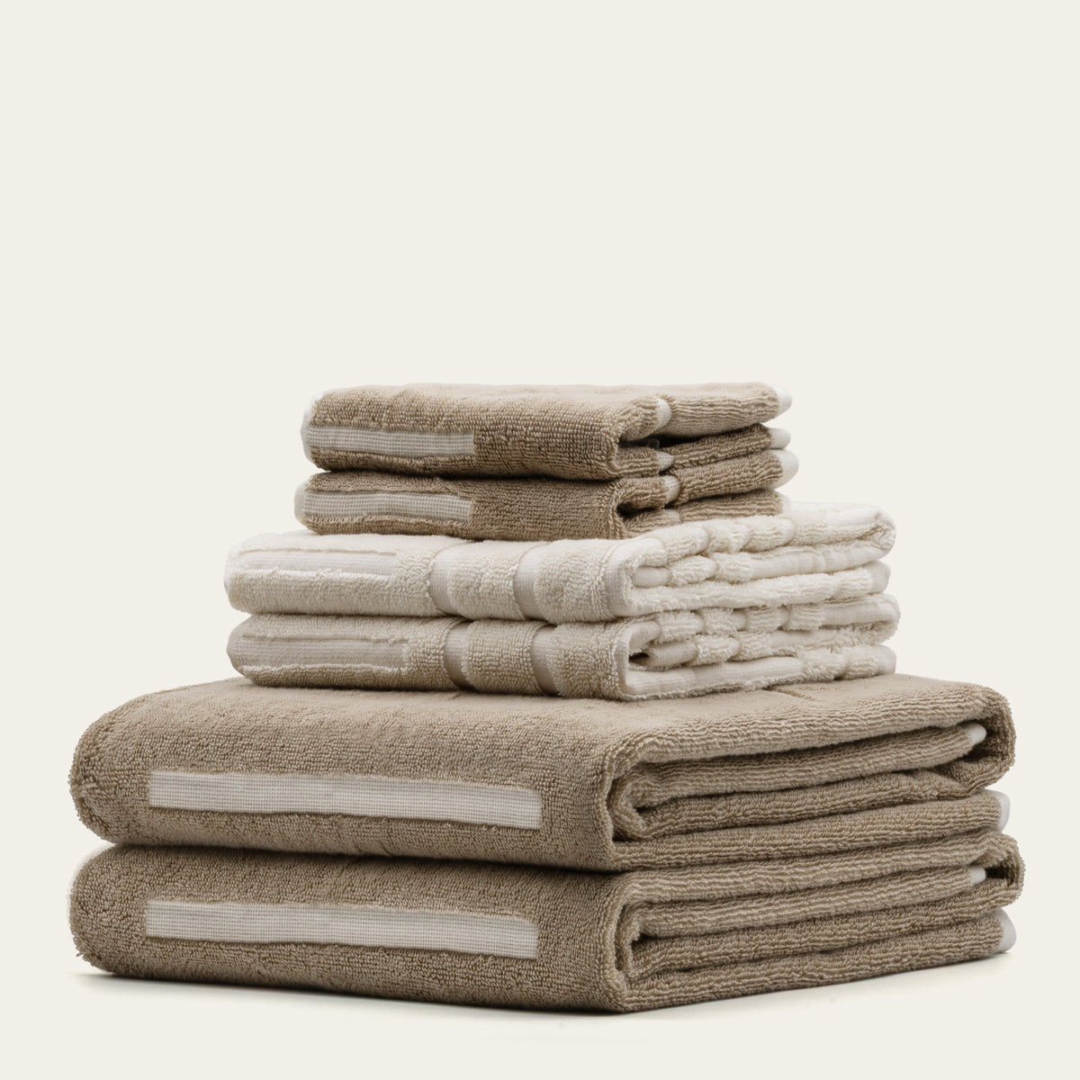 Mixed tan and ecru cotton towel stacks with embroidered-looking accent strips