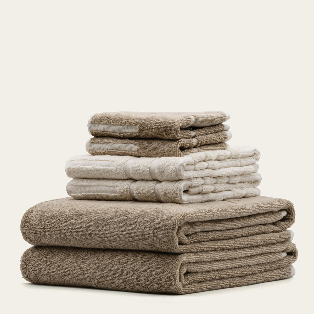 Assorted stack of tan and ecru cotton towels, including white-striped styles