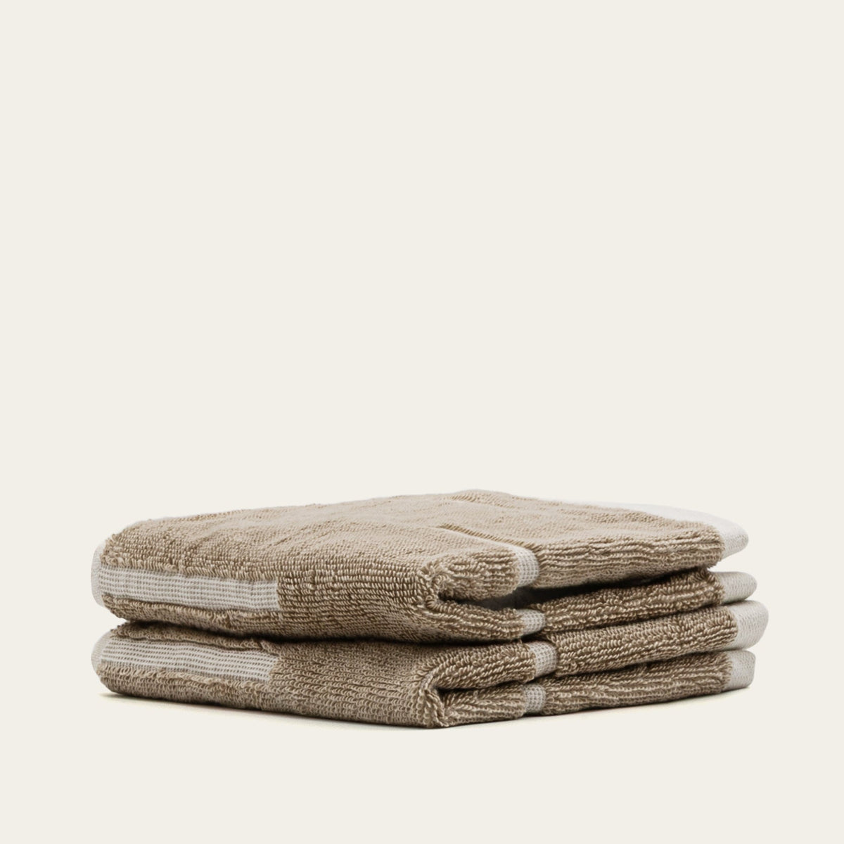 Folded tan cotton towels with contrasting ecru horizontal stripe detail