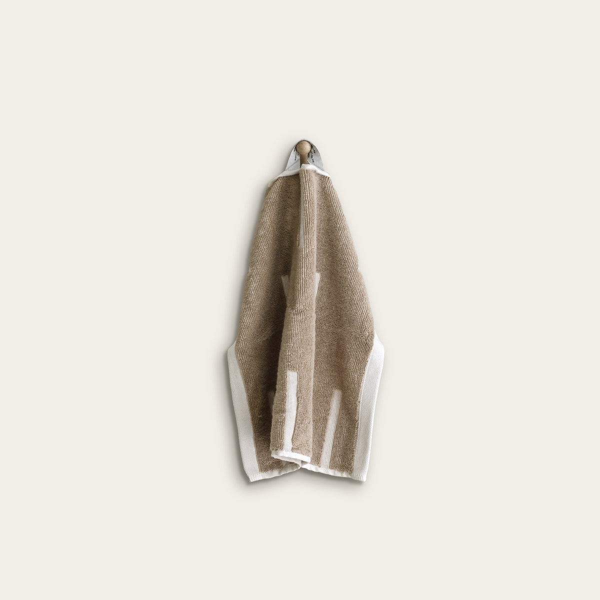 Tan and ecru cotton washcloth with white striped border, folded with hanging loop
