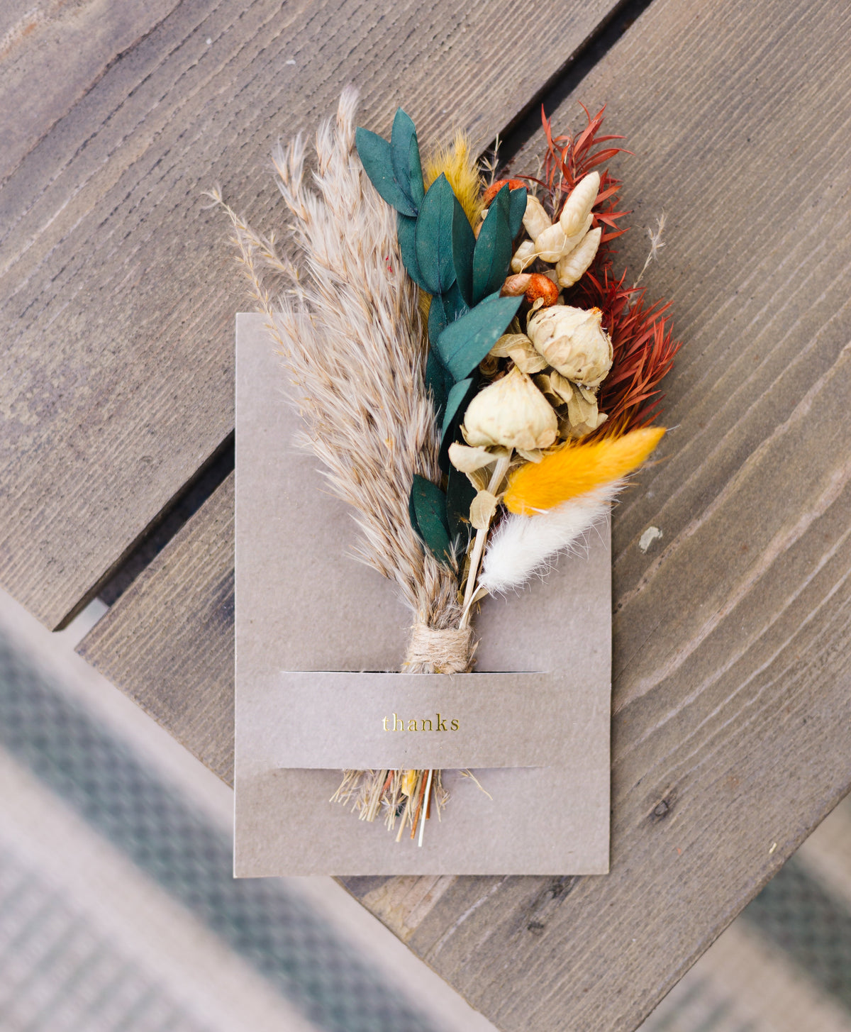 Mini dried floral greeting card with dried pampas, teal leaves, orange accents and “thanks”