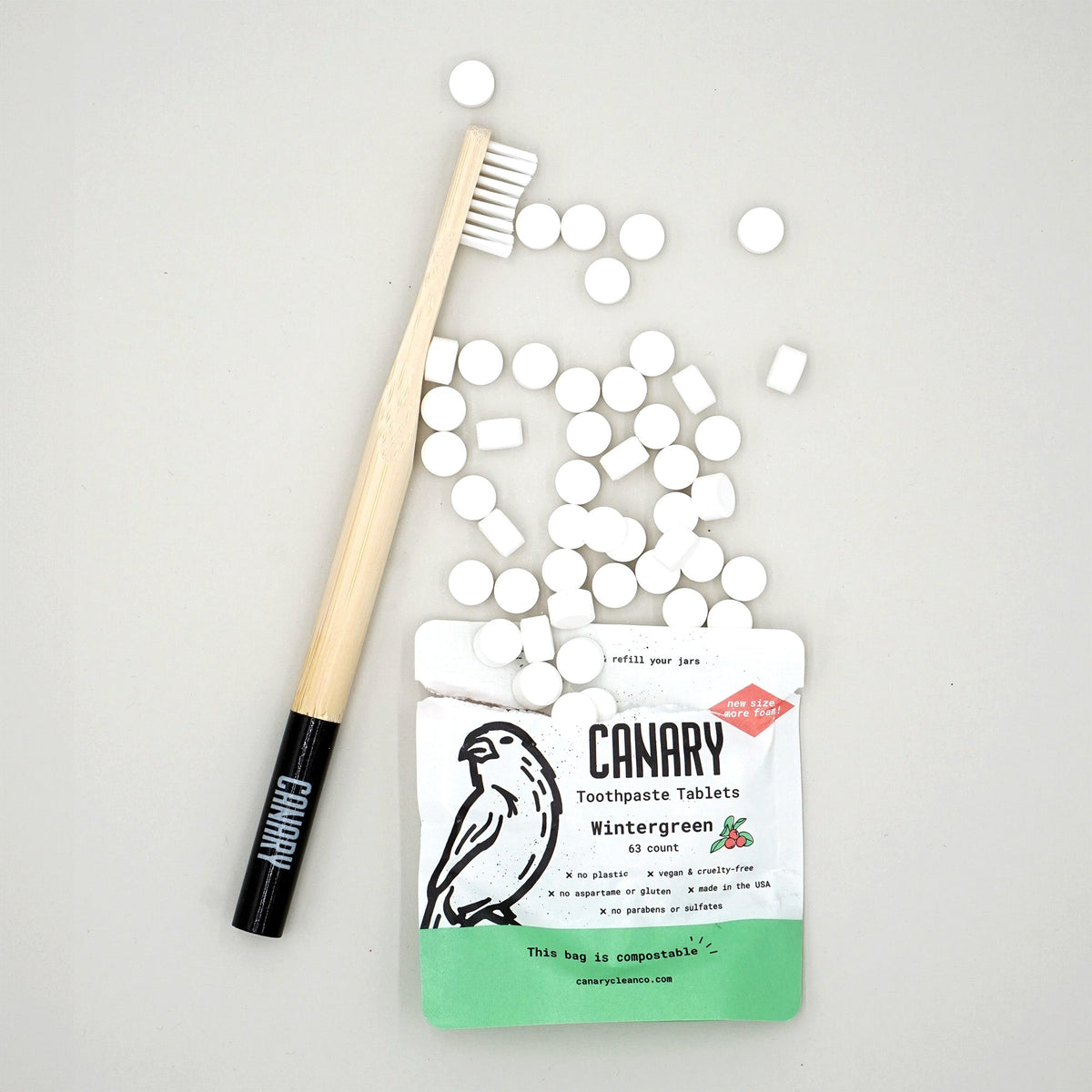Canary Wintergreen toothpaste tablet pouch with loose tablets and a bamboo toothbrush